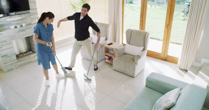 Home dance, cleaning broom and happy couple hygiene routine, living room performance and having fun together. Love, housekeeping mop and marriage people rhythm, support and partner sweeping floor