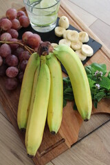Régime de banane, bananes et fruits frais sur plateau en bois
