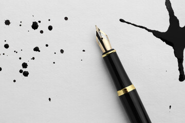 Stylish fountain pen on paper with blots of ink, top view