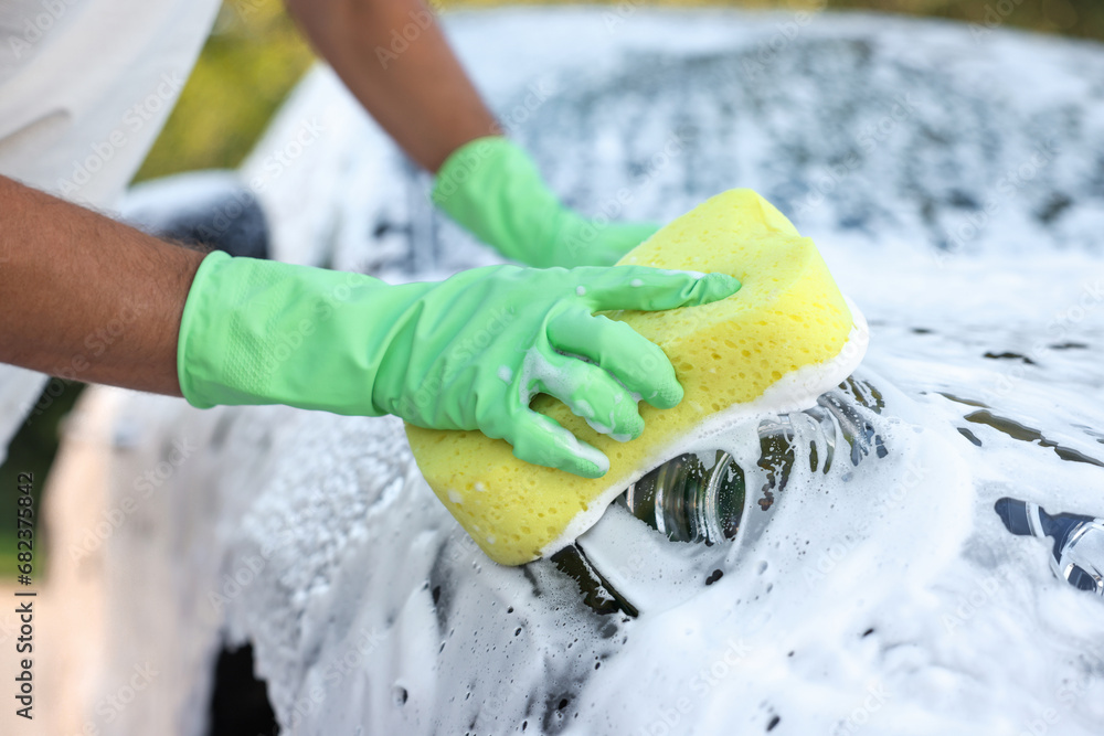 Wall mural man washing car with sponge outdoors, closeup