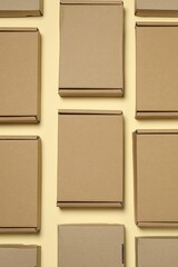 Fototapeta premium Many closed cardboard boxes on pale yellow background, flat lay