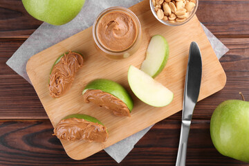 Slices of fresh green apple with peanut butter on wooden table, flat lay