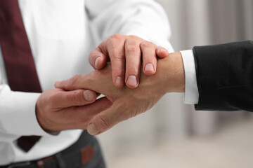 Trust and deal. Men joining hands indoors, closeup