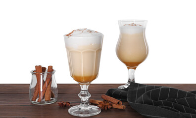 Delicious eggnog in glasses and spices on wooden table against white background