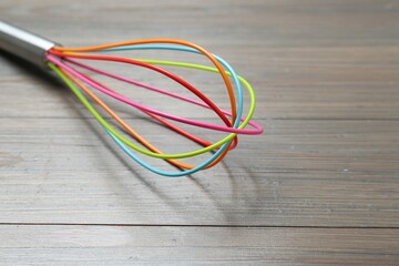One whisk on wooden table, closeup. Space for text