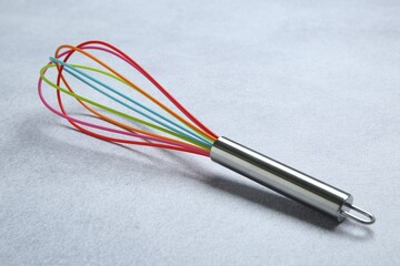 Bright whisk on gray table. Kitchen tool