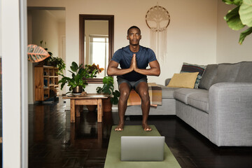 African man in the chair pose during an online yoga class
