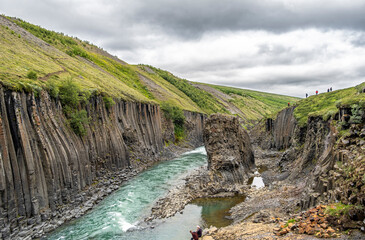 Jokla River cuts through the Studlagil canyon and passes by the hexagonal basalt columns caused by...