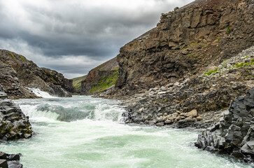Jokla River cuts through the Studlagil canyon and passes by the hexagonal basalt columns caused by...