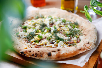 Freshly baked pizza with egg, sausage and fresh herbs, chives and dill. Country style pizza, selective focus.