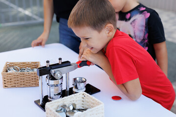 Mechanical manual press. The boy makes a badge