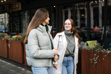 Friends digital detox. Two friends enjoy a face-to-face conversation on city sidewalk, digital detox by engaging in personal interaction without the distraction of smartphones.