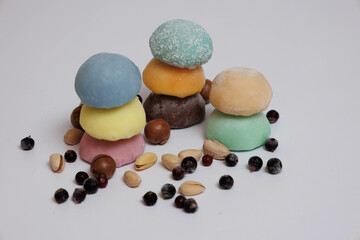 Fototapeta na wymiar Japanese rice desert mochi closeup. Colouful mochi cakes sliced. Tasty fruit and chocolate mochi on grey background. Traditional cold ice asian candy. Dry fruits and nuts.