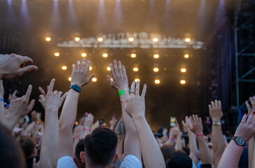 Large concert. Audience cheering and dancing with hands raised up to the sky