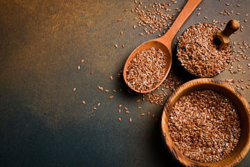 Wooden spoon with flax seeds, on a dark background. Organic food, superfood. Top view.