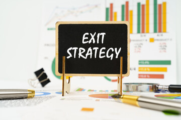 Against the background of business graphs, a board with the inscription - Exit Strategy
