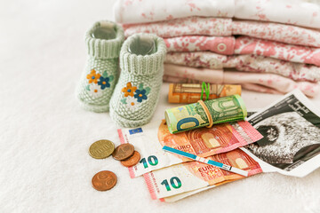 Pregnancy planning. Pregnancy test, money, ultrasound photo of a child and baby clothes on a white background, price for IVF, money for a child, government payments for a child, medical insurance