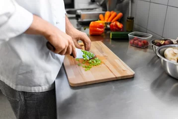 Fotobehang cooking food, profession and people concept - close up of male chef with knife chopping celery on cutting board at restaurant kitchen © Syda Productions