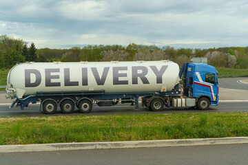 On a tank truck driving along the road there is an inscription - Delivery