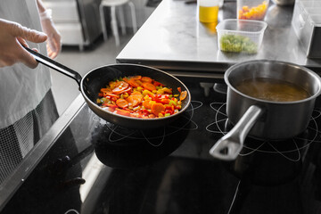 cooking food, profession and people concept - close up of male chef with frying pan stewing vegetables at restaurant kitchen