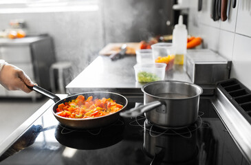 cooking food, profession and people concept - close up of male chef with frying pan stewing vegetables at restaurant kitchen