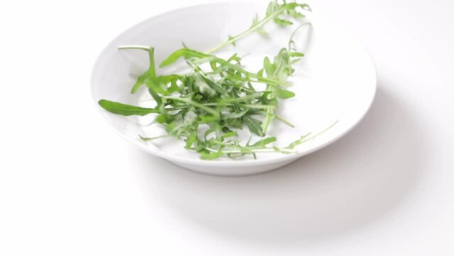 rugula rocket leaves falling in white plate