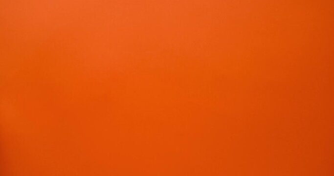 Ringing alarm clock in hand on an orange background. 4K stop motion animation