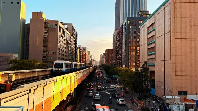 4k footage of Wenhu or Brown line of Taipei MRT in Taiwan. The train running on elevated rails of the Taipei Metro System between buildings during sunset.
