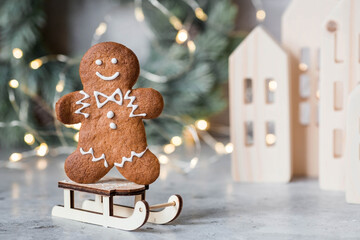 Homemade gingerbread Christmas cookies in icing sugar. Delicious gingerbread cookies on the background of a bokeh of Christmas tree lights. Freshly baked Christmas gingerbread cookies. - obrazy, fototapety, plakaty