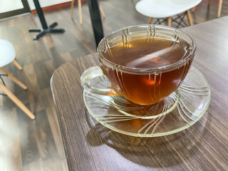 A cup of hot tea with puffs of smoke in a transparent glass on a table in a waiting room. Concept for relaxation, breakfast and working breaktime