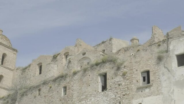 CRACO, ITALY - MAY 2, 2023: panning shot, the ruined walls and windows of some houses of the abandoned town, detail.
