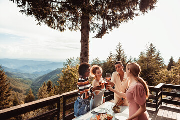 Friends Toasting with drinks on balcony with nature landscape