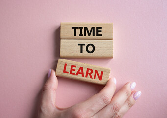 Time to learn symbol. Wooden blocks with words Time to learn. Beautiful pink background. Businessman hand. Business and Time to learn concept. Copy space.