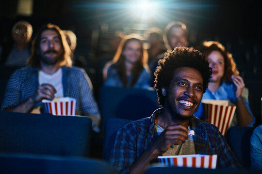 Smiling young man watching a movie in theater