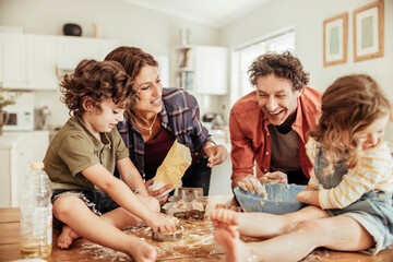 Young family with small children baking together in kitchen having fun