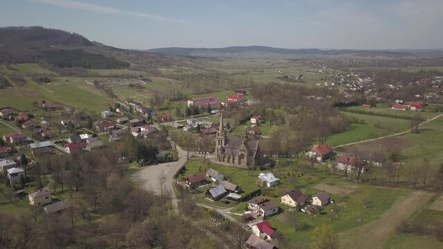 Cieklin, Poland - 4 9 2019: Panorama of a small European village with a Christian Catholic church in the center. Farms among green picturesque hills. Panorama of the Carpathian region with a drone