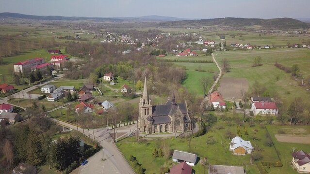 Cieklin, Poland - 4 9 2019: Panorama of a small European village with a Christian Catholic church in the center. Farms among green picturesque hills. Panorama of the Carpathian region with a drone