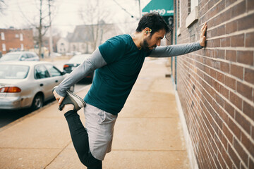 Athletic man stretching foot outside