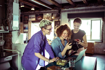 Young women going over the photos in a dslr camera while working in a startup company office and having a lunch break