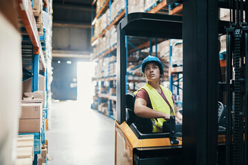 Woman operating forklift in large warehouse