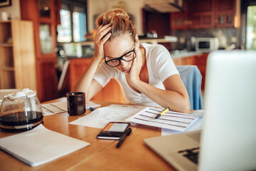 Young woman struggling with paying bills at home