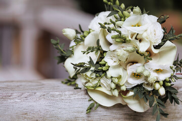 A beautiful bouquet of white roses and lilies with green leaves on a wooden surface. Ideal for wedding, anniversary, or birthday gifts. Concept for expressing love and appreciation with opy space.