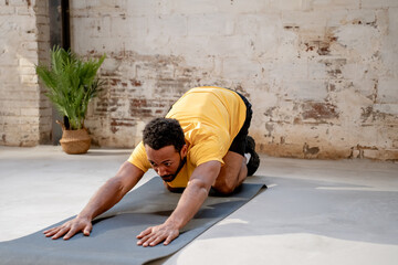 Young man practicing yoga, stretching back sitting pose in a industrial gym. High quality photo
