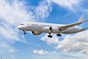 Passenger plane landing at the airport, under a blue sky with white clouds