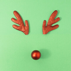 Reindeer antlers with christmas ball on green background. Christmas minimal Greeting card.