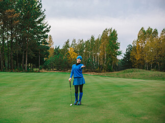 Female golfer holding golf club and ball looking at camera