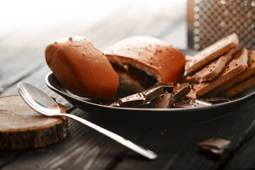 The concept of sweets. Cookies, chocolate and bun on a wooden table. For coffee and tea