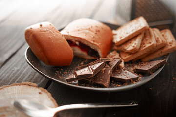 The concept of sweets. Cookies, chocolate and bun on a wooden table. For coffee and tea