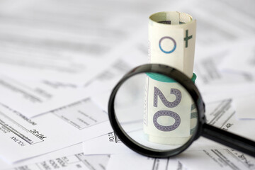 Polish zloty money and magnifying glass on big amount of polish tax forms close up. Accounting,...