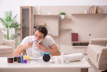 Young man shaving face at home